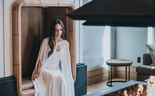 Woman in wedding sitting by fire in Schofield hotel lobby